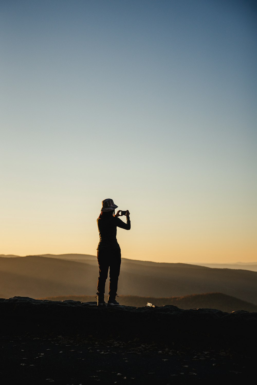 Silhouette eines Mannes, der während des Sonnenuntergangs auf dem Gipfel des Berges steht