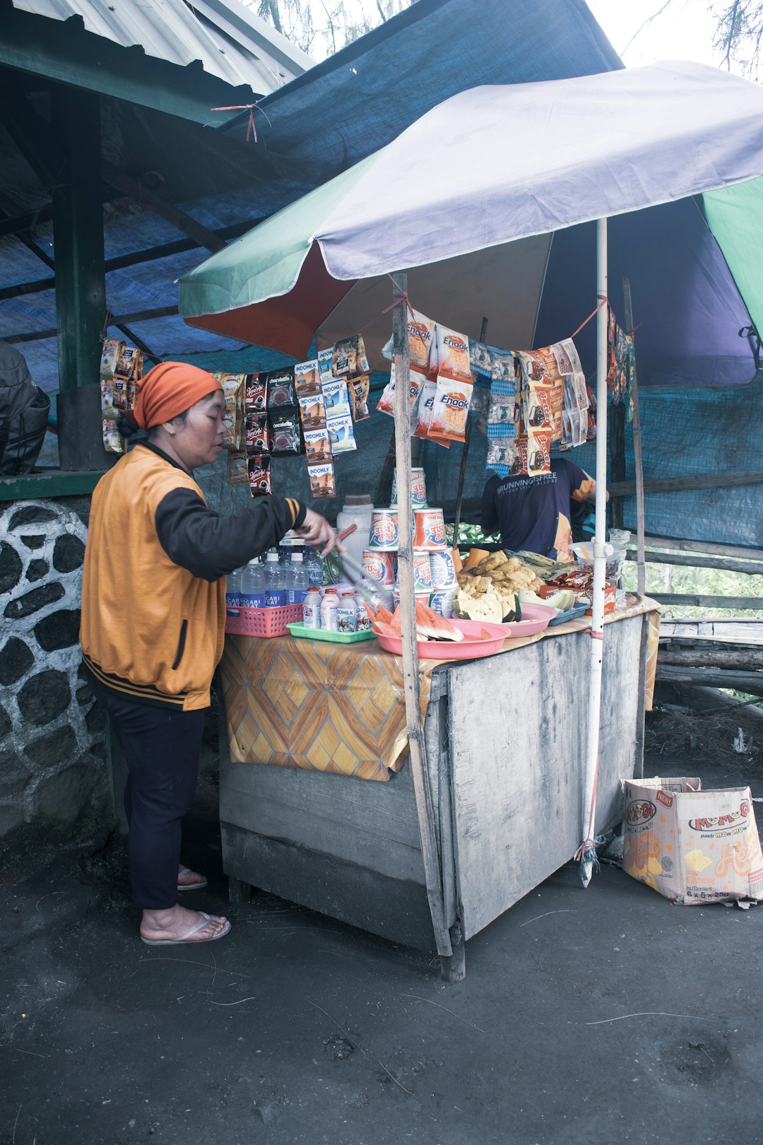 man in brown long sleeve shirt standing in front of food stall