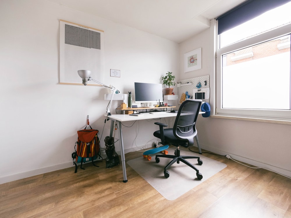 black office rolling chair beside white wooden desk