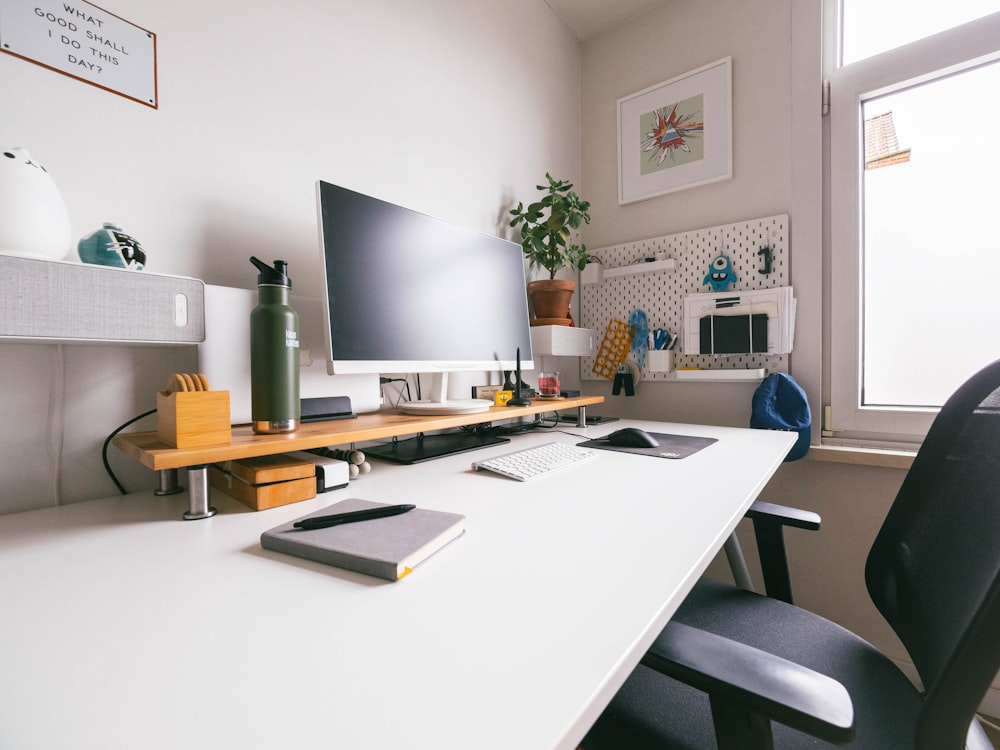 Moniteur d’ordinateur à écran plat argenté sur un bureau en bois blanc