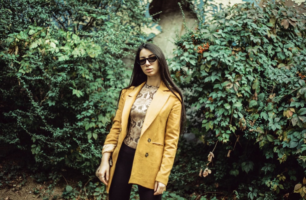 woman in yellow coat standing near green leaf plant