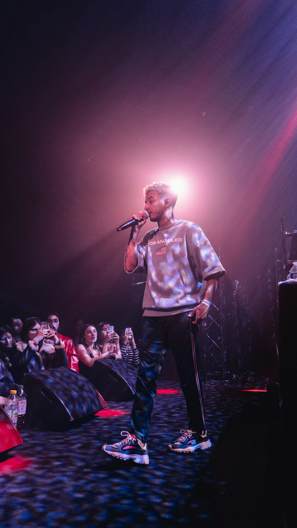 man in white crew neck t-shirt singing on stage