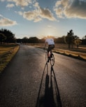 man in white shirt riding bicycle on gray asphalt road during daytime