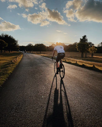 man in white shirt riding bicycle on gray asphalt road during daytime