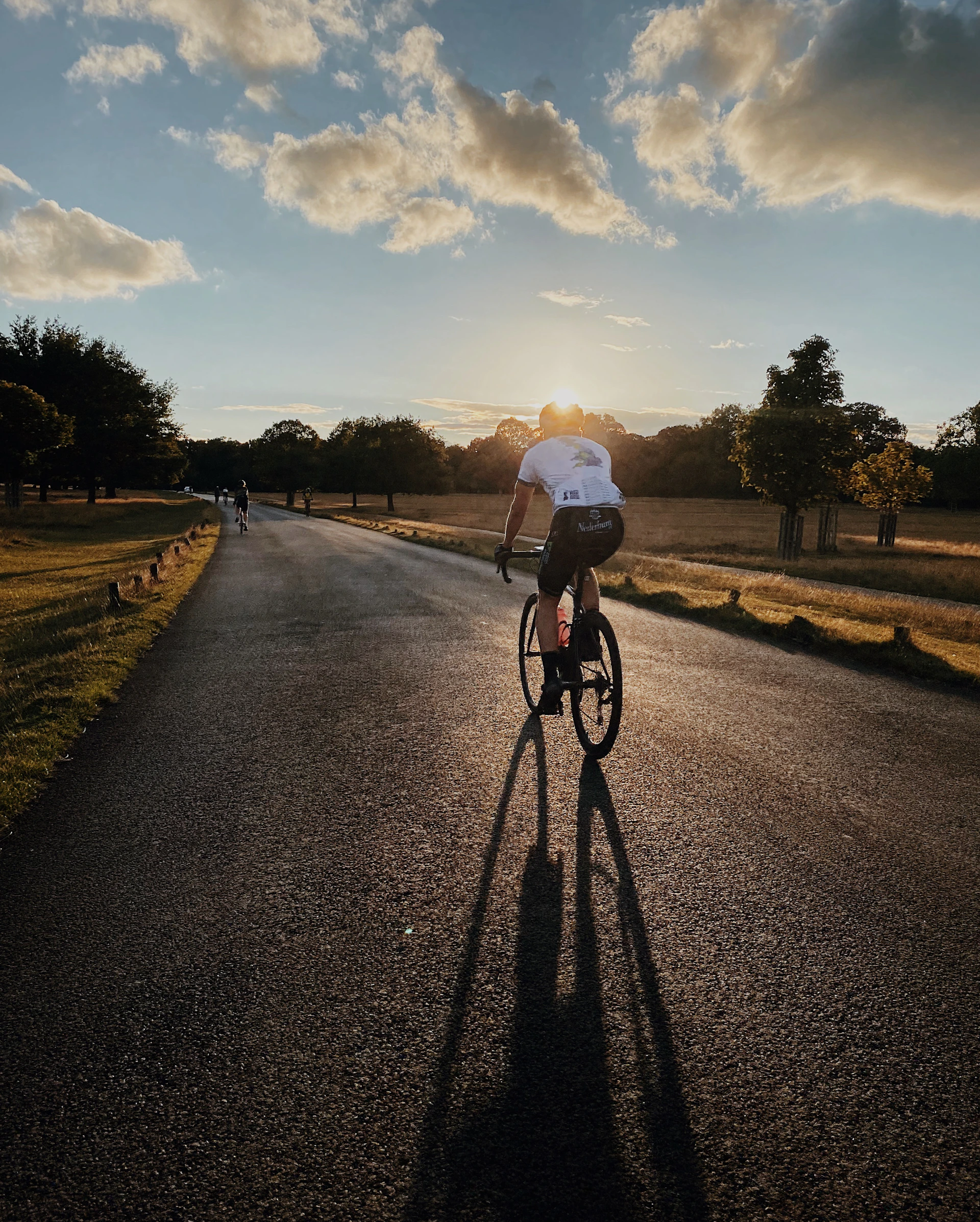 man in white shirt riding bicycle on gray asphalt road during daytime