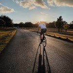 man in white shirt riding bicycle on gray asphalt road during daytime