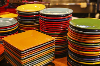 Stack of colorful krep pans with wooden handles on a rustic table