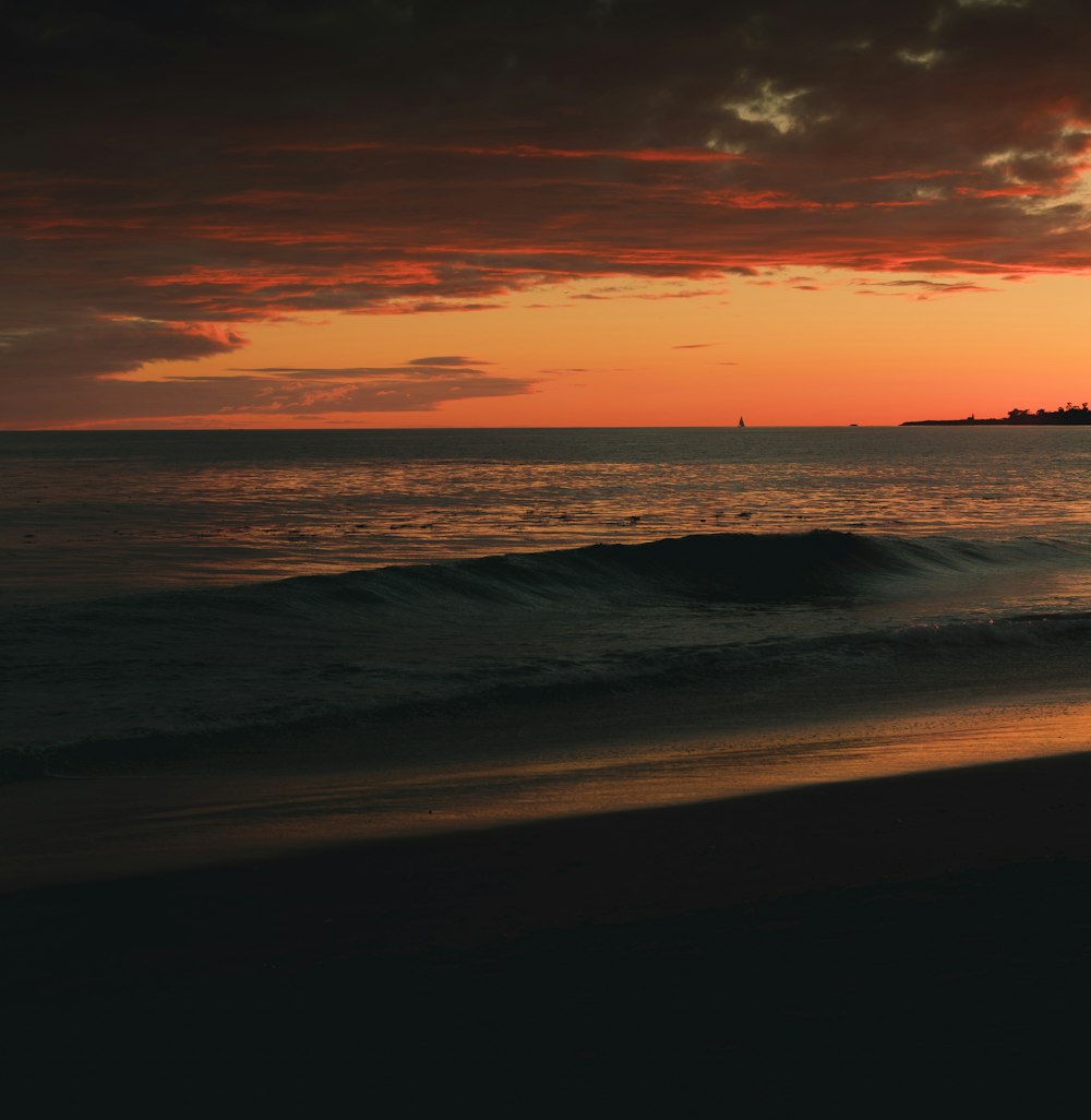 sea waves crashing on shore during sunset