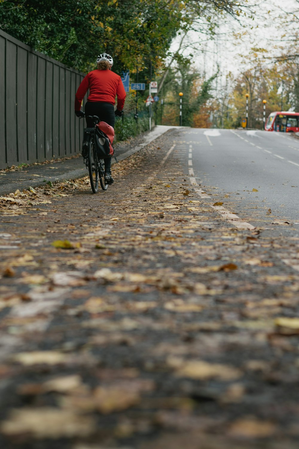homem na jaqueta vermelha que monta a bicicleta na estrada durante o dia
