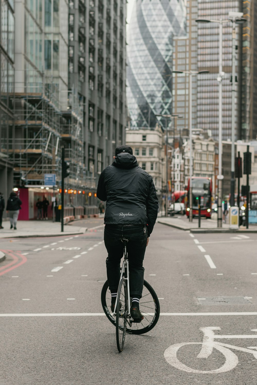 昼間、道路を自転車で走る黒い革ジャンを着た男性