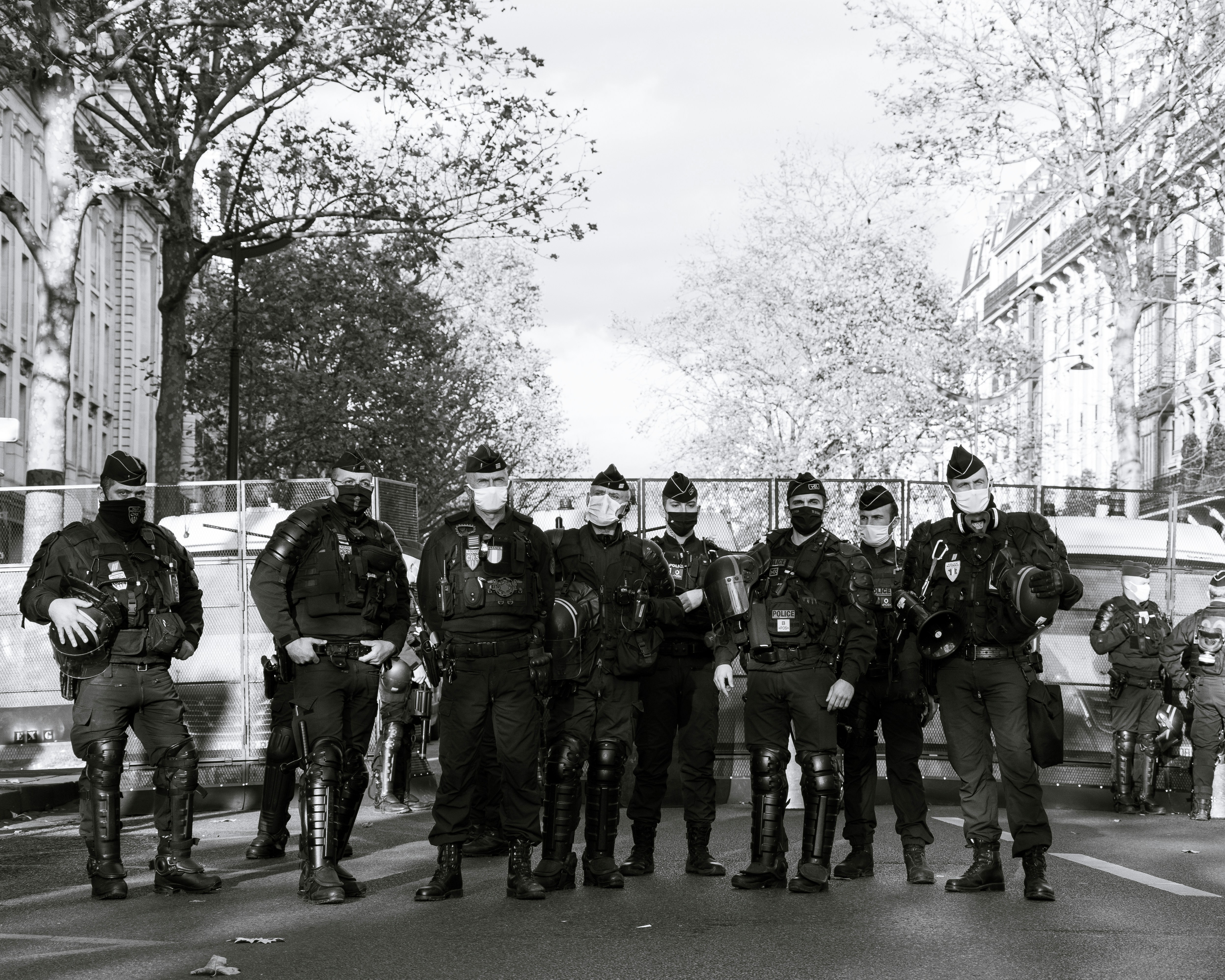 grayscale photo of men in black and white camouflage uniform standing on road