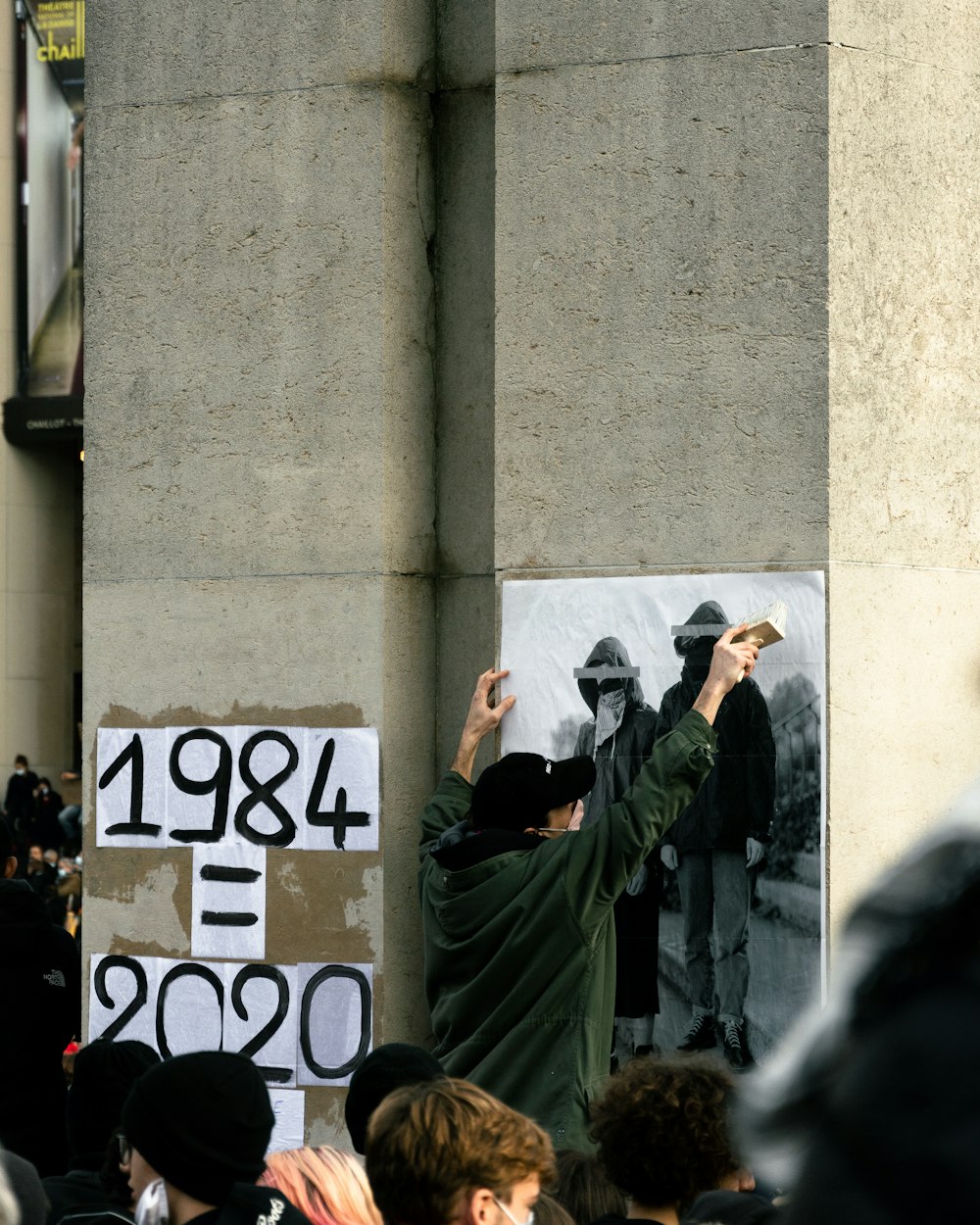 man in green coat holding black smartphone