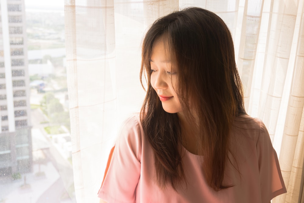 woman in pink shirt standing near white tiled wall