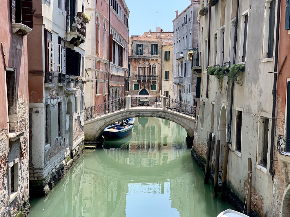 Barca blu sul fiume tra edifici in cemento durante il giorno