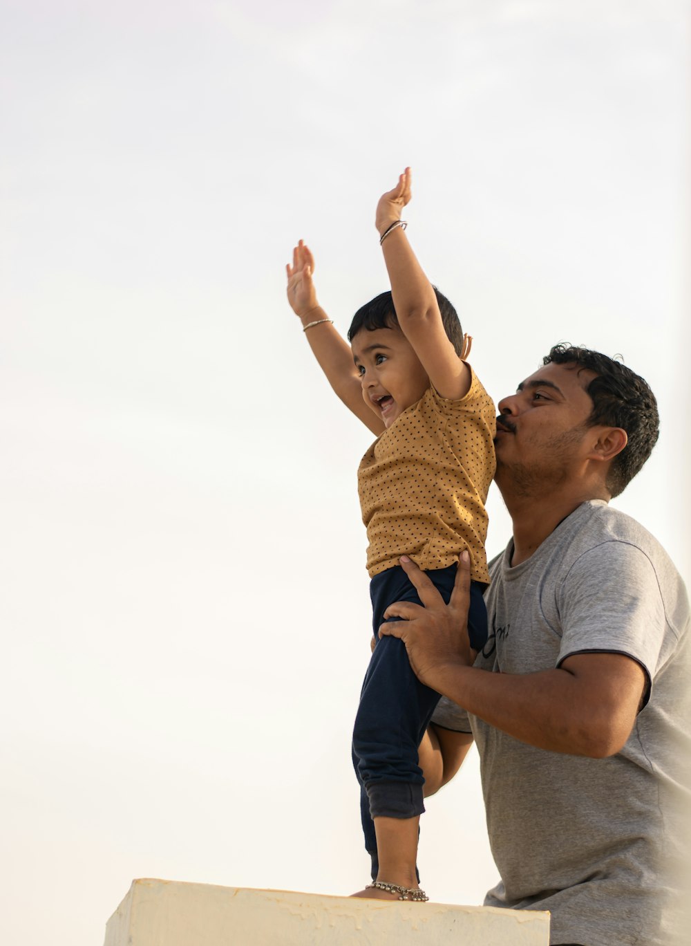 man in white crew neck t-shirt carrying girl in yellow and black tank top during