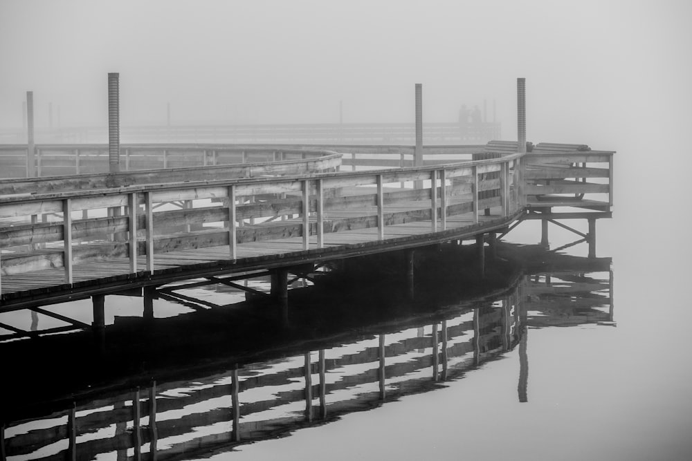 grayscale photo of wooden dock on water