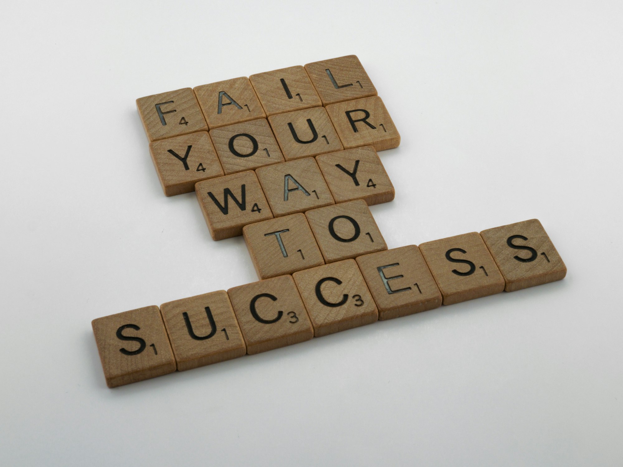Scrabble pieces spelling out "fail your way to success".