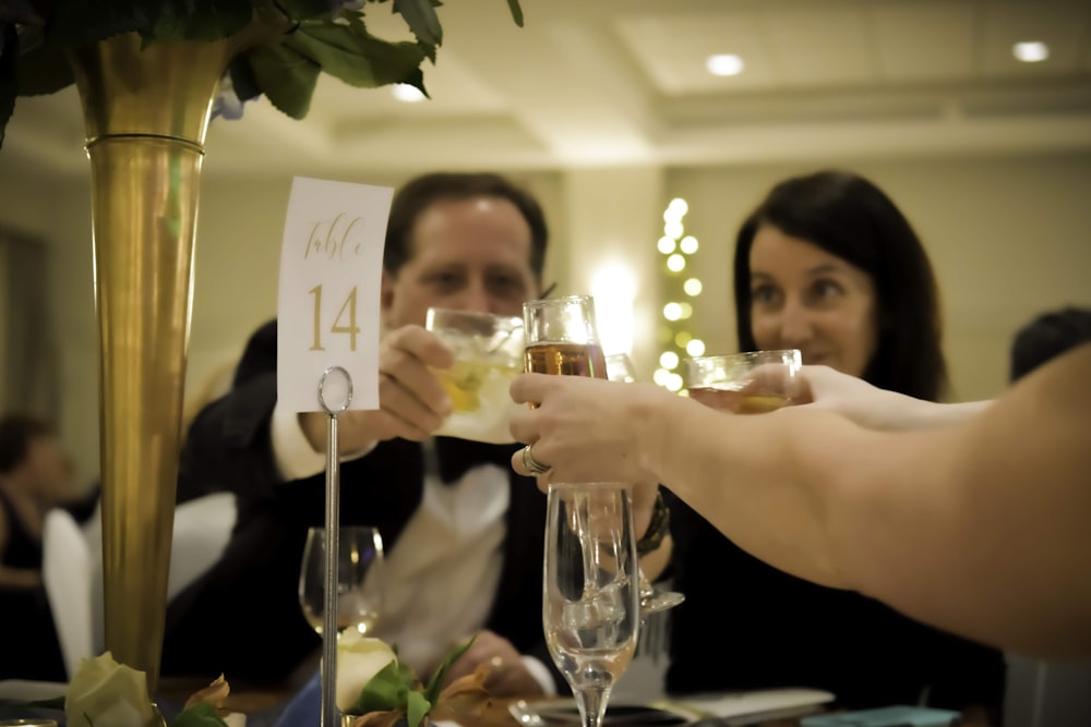 people holding white card and drinking glasses