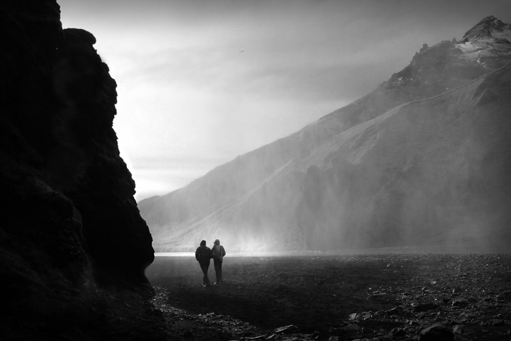 昼間、山の近くの岩場に立つ2人
