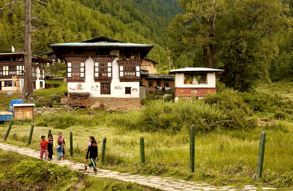 2 people walking on pathway near white and brown concrete building during daytime