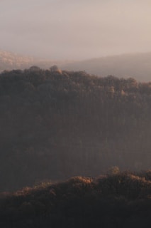A peaceful dawn over the hills with soft light illuminating the horizon.