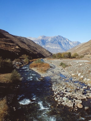 A nature-themed coloring page featuring mountains and a river.
