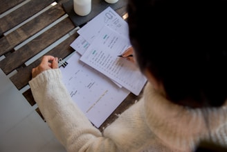 person in white long sleeve shirt writing on white paper