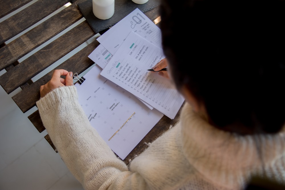 person in white long sleeve shirt writing on white paper