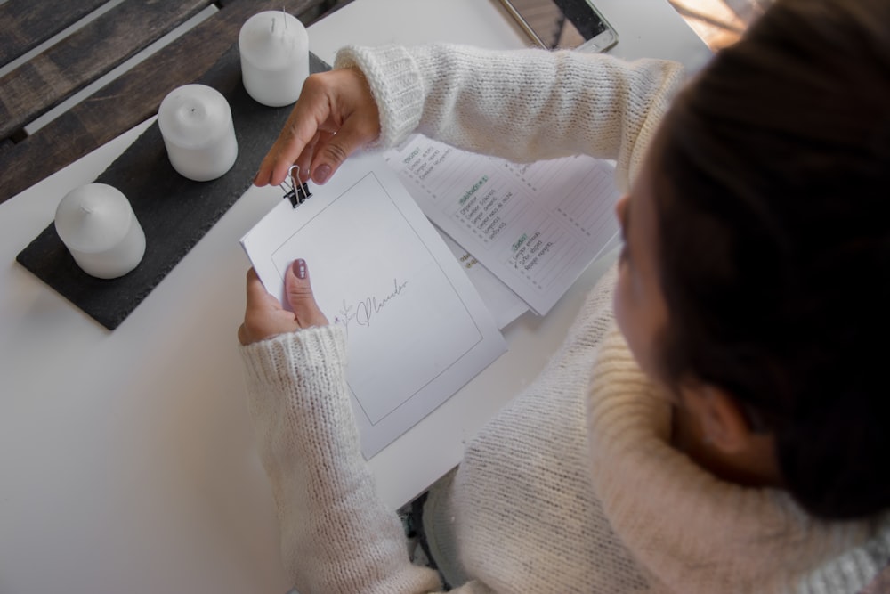 person in white long sleeve shirt holding white printer paper