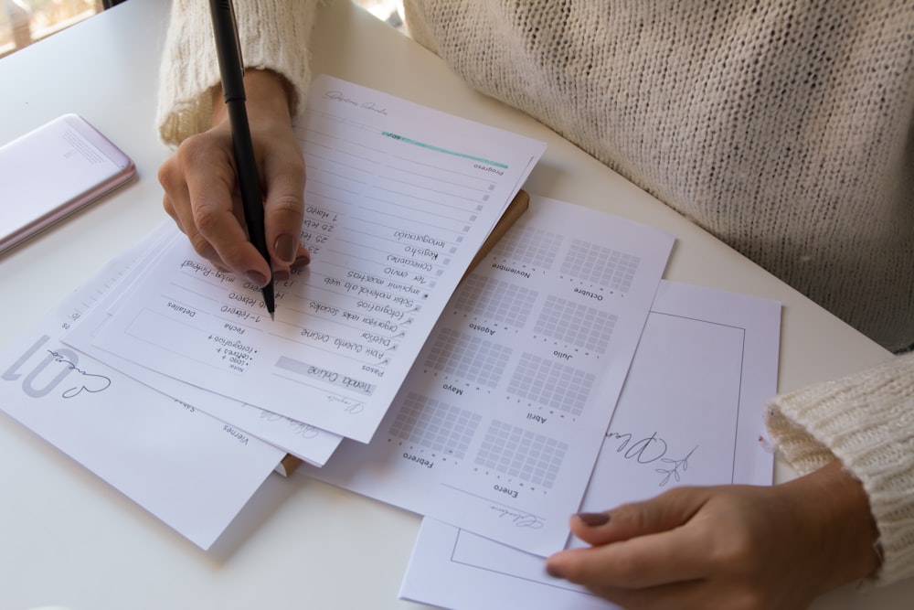 personne écrivant sur du papier blanc