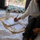person in gray sweater writing on white paper