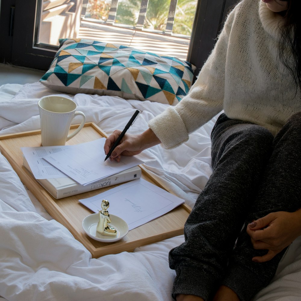 person in gray sweater writing on white paper