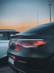 A sleek luxury car being carefully loaded onto a transport truck at dawn.