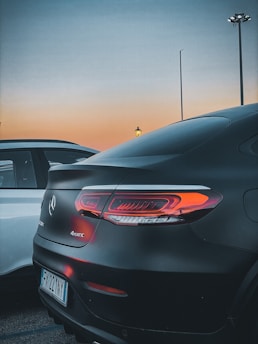 A sleek luxury car being carefully loaded onto a transport truck under soft evening light.