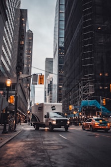 white van on road near high rise buildings during daytime