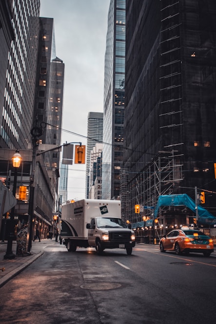 white van on road near high rise buildings during daytime