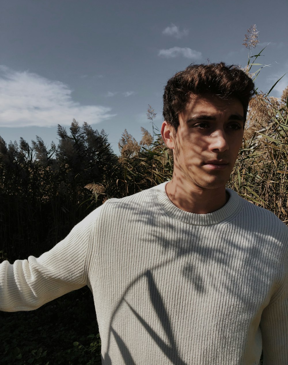 man in white crew neck long sleeve shirt standing near green trees during daytime