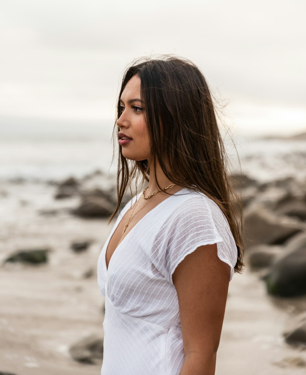 femme en chemise blanche debout sur la plage pendant la journée