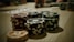 Stacks of poker chips are arranged on a wooden table, with various denominations and colors such as red, green, and black. Some playing cards are blurred in the background, indicating a game setting.