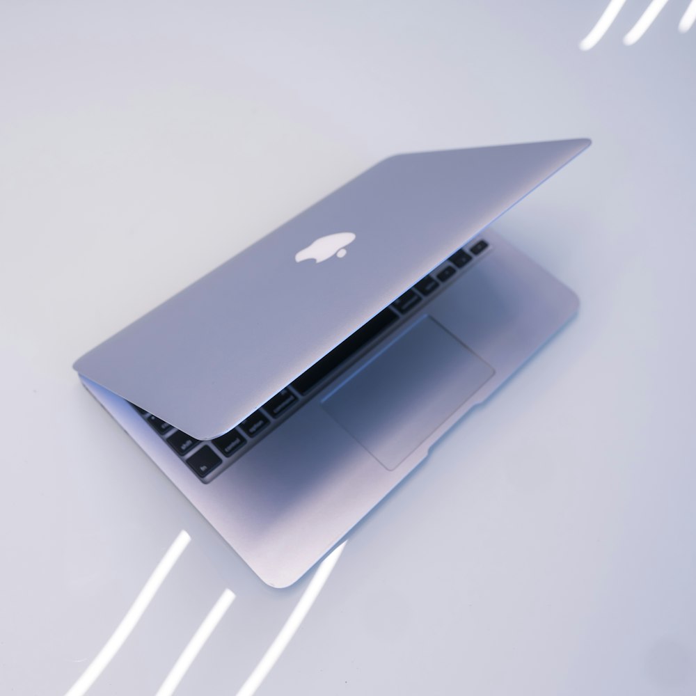 MacBook plateado sobre mesa blanca