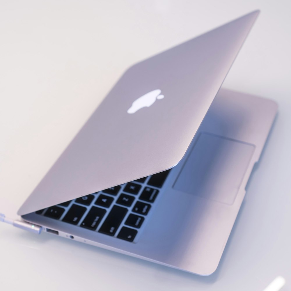 silver macbook on white table