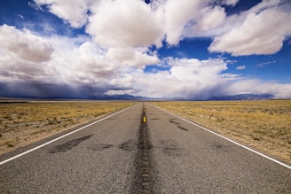gray concrete road under blue sky and white clouds during daytime