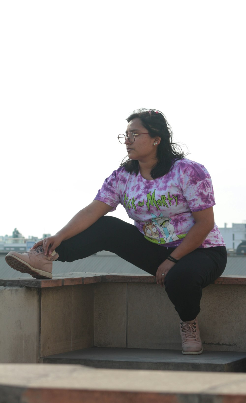 woman in purple and white floral shirt and black pants sitting on concrete bench during daytime