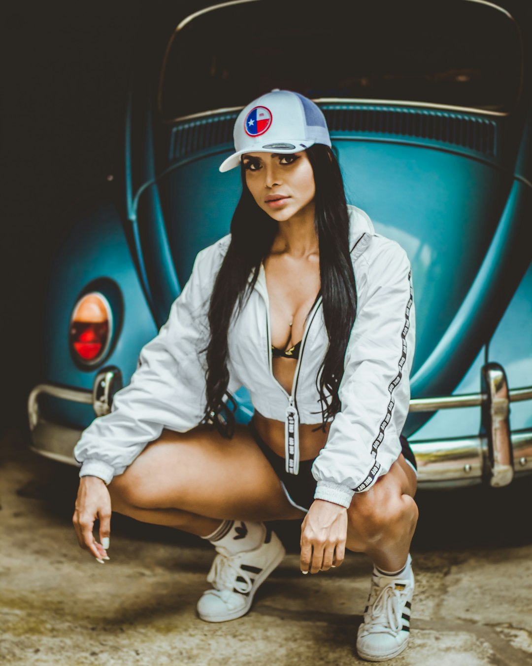 woman in white jacket and brown shorts sitting on blue car