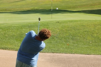 Golf player aiming at a distant hole on a sunny driving range.