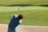 A smiling golfer practicing their swing on the course.