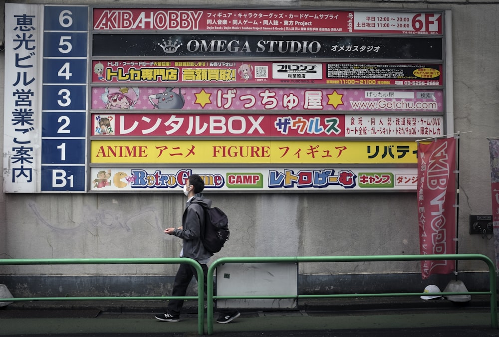 man in black jacket sitting on green metal bench