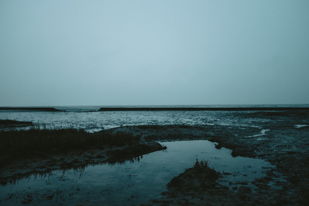 body of water under gray sky,