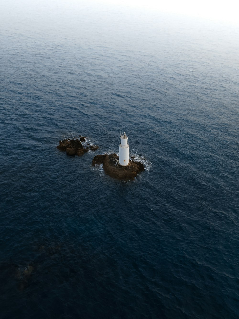 昼間の海の真ん中にある茶色の岩層の白と茶色の灯台