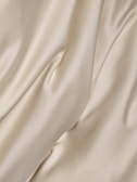 Cream-colored fabric with soft folds and a smooth texture creates a gentle flow across the surface.